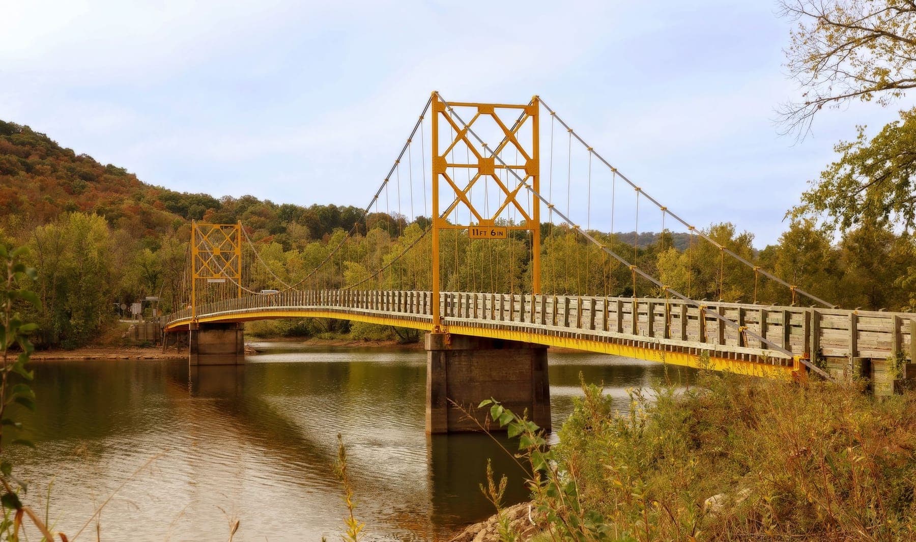 The yellow one-lane Beaver Bridge suspension span over the White River in fall