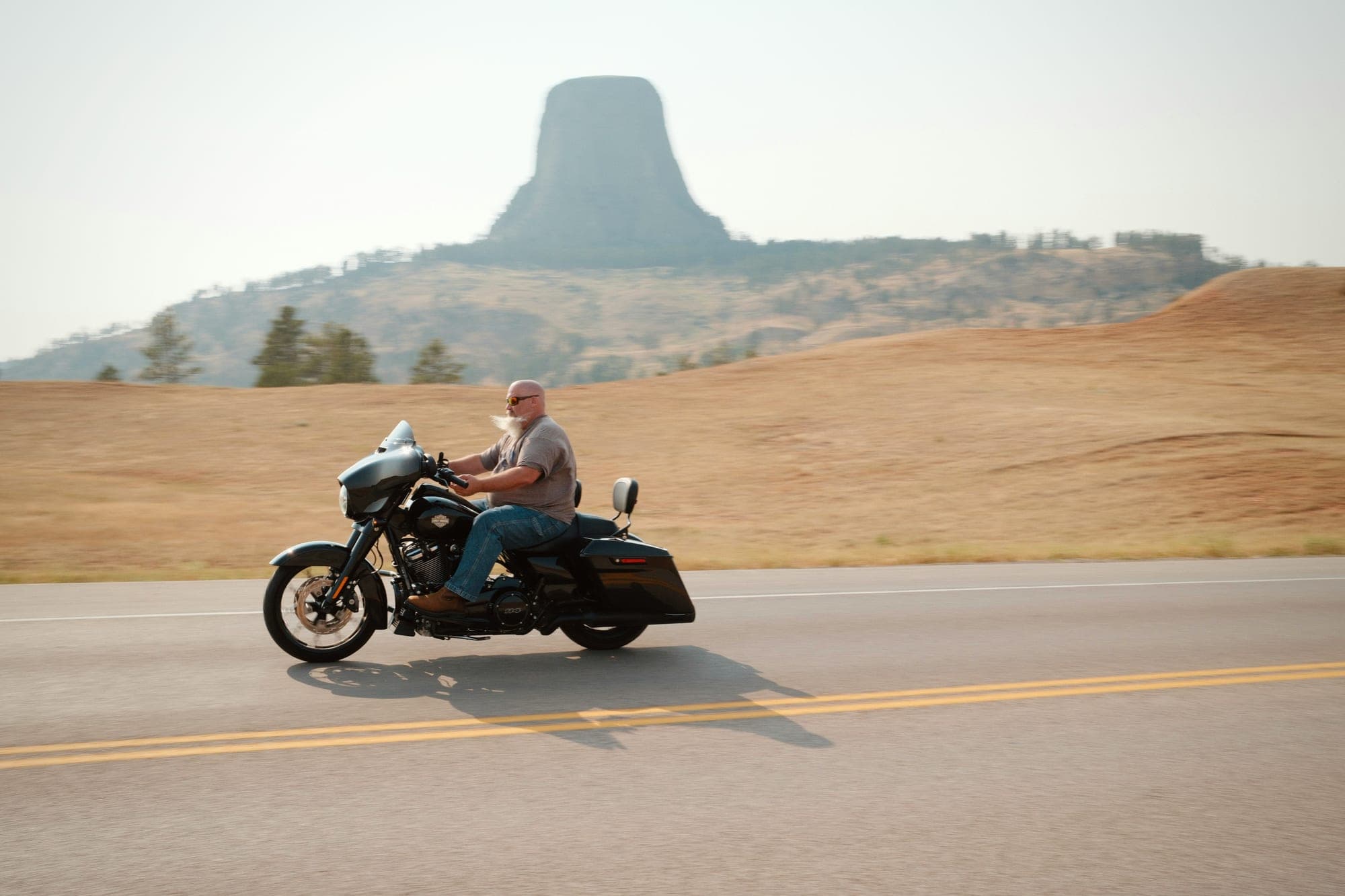 A rider on a bagger passing Devils Tower, Wyoming