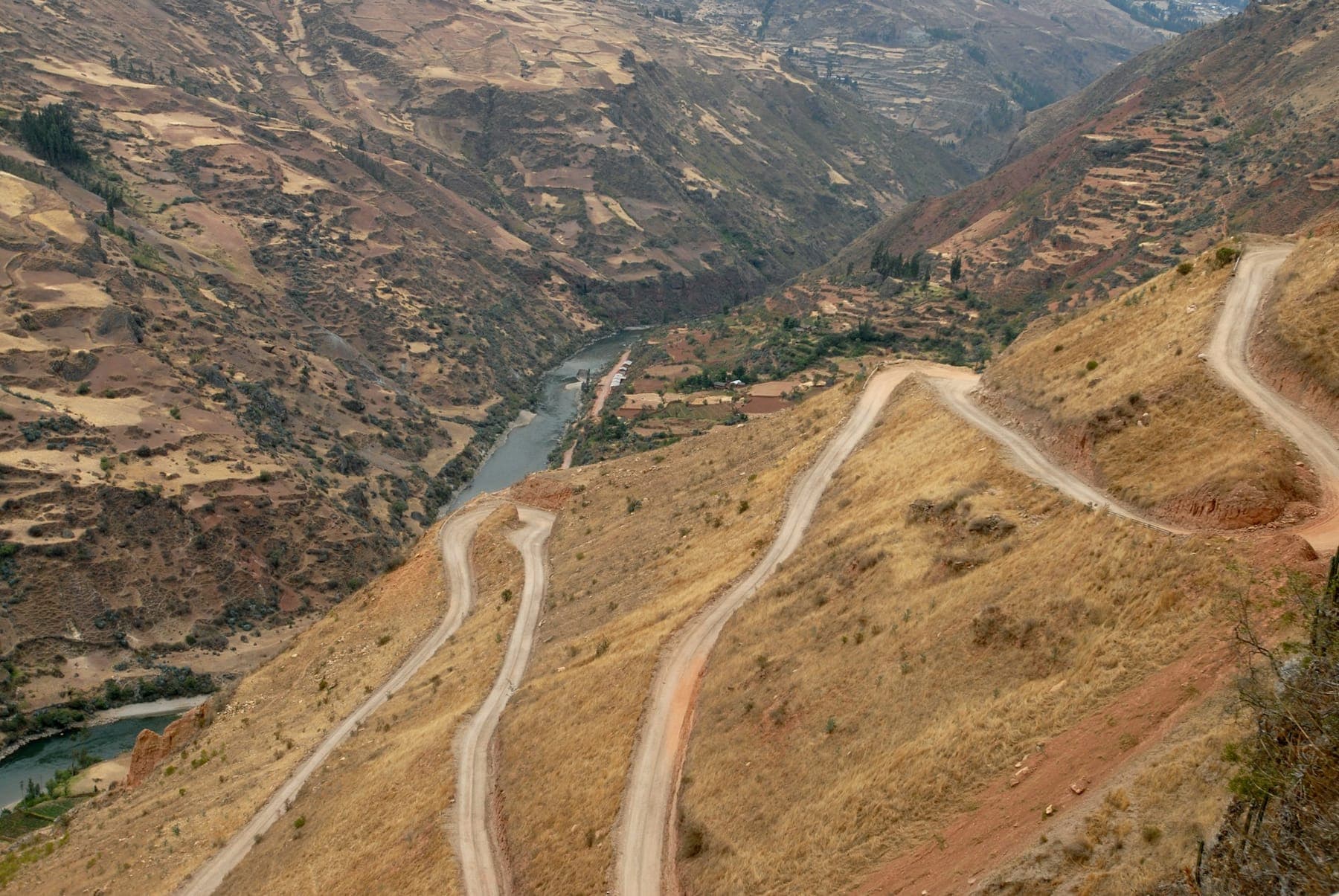 A dirt road switchbacking down a dry canyon in the Peruvian highlands, seen from above