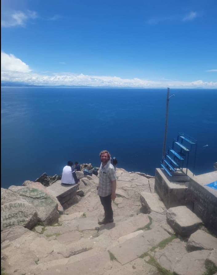 Ross on a stone terrace above the deep blue water of Lake Titicaca