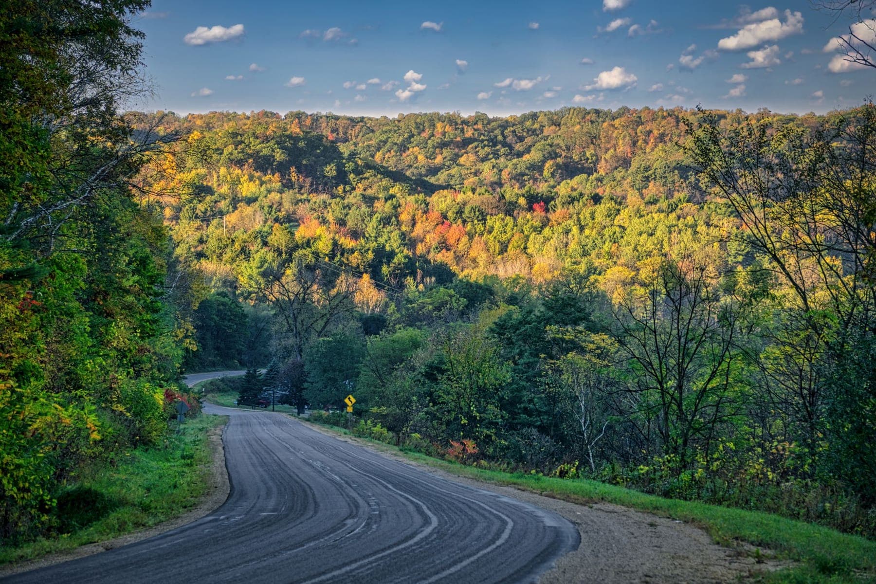 A two-lane road winding through fall color in the Driftless hills near Nelson, Wisconsin
