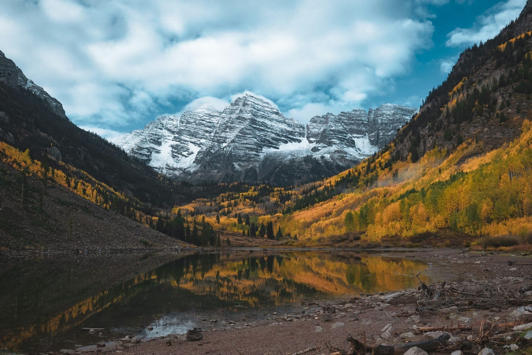 The Maroon Bells dusted with fresh snow above golden aspens and Maroon Lake