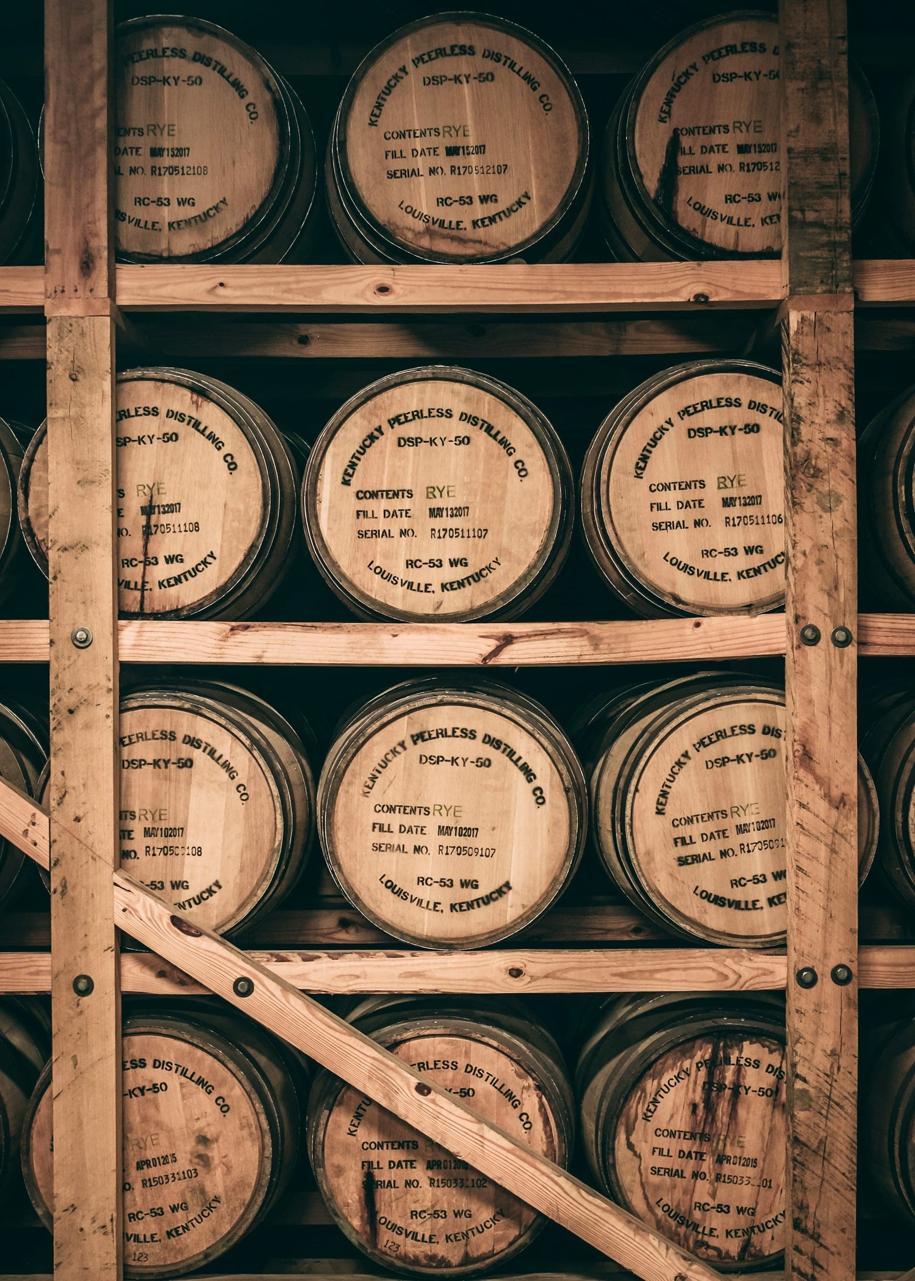 Bourbon barrels stamped Louisville, Kentucky, resting on rickhouse racks
