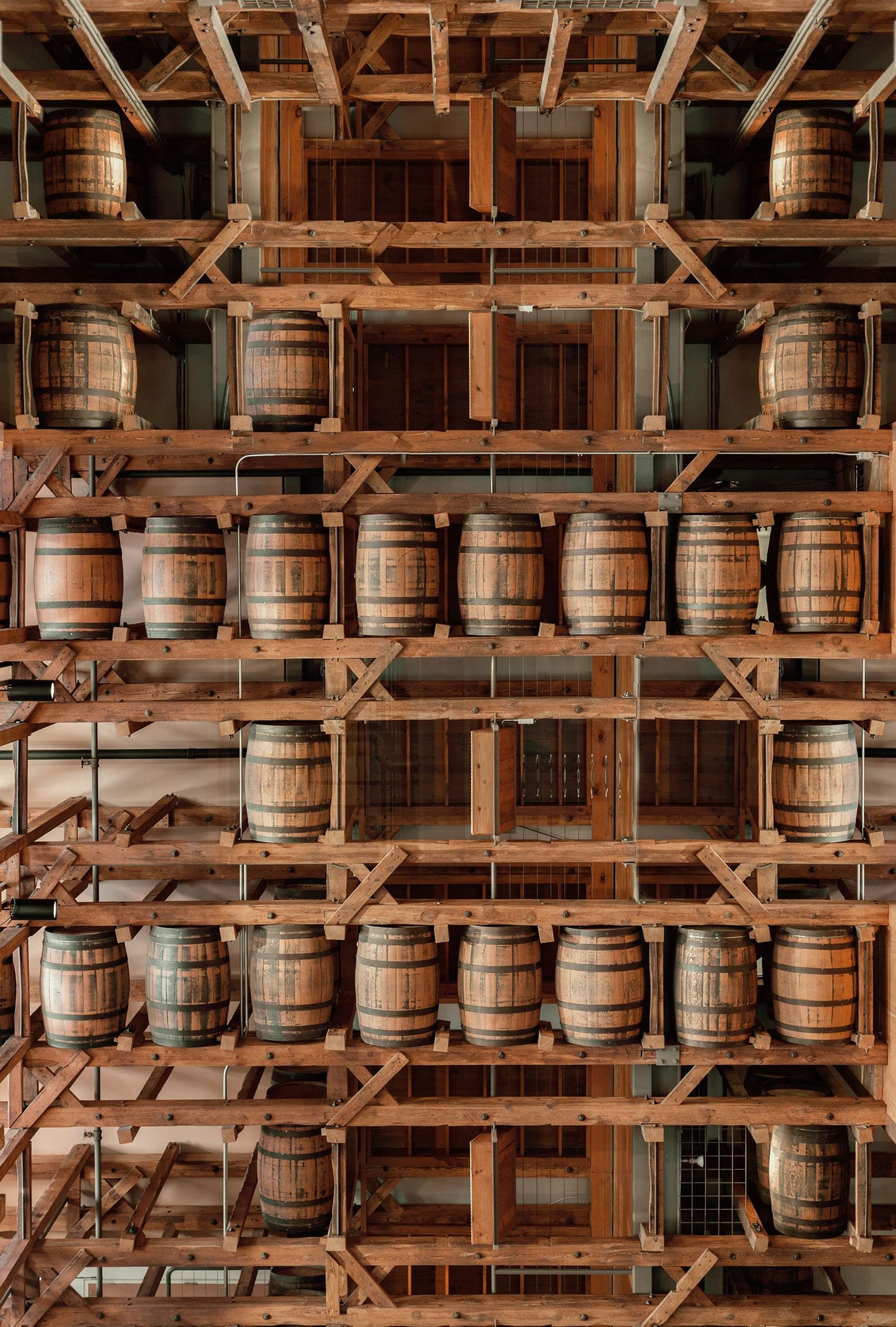 Rows of whiskey barrels stacked on wooden racks inside a rickhouse