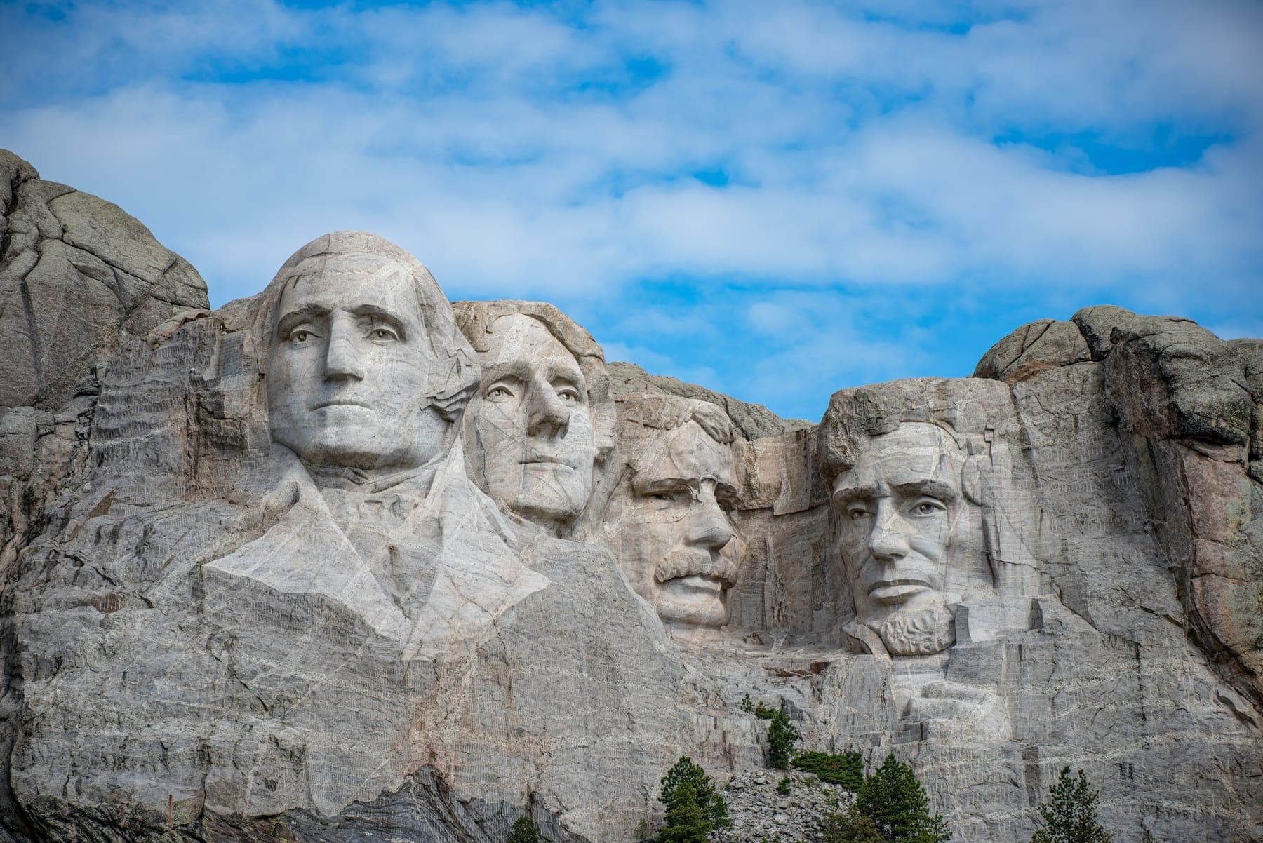 The four presidents of Mount Rushmore against a blue sky with white clouds