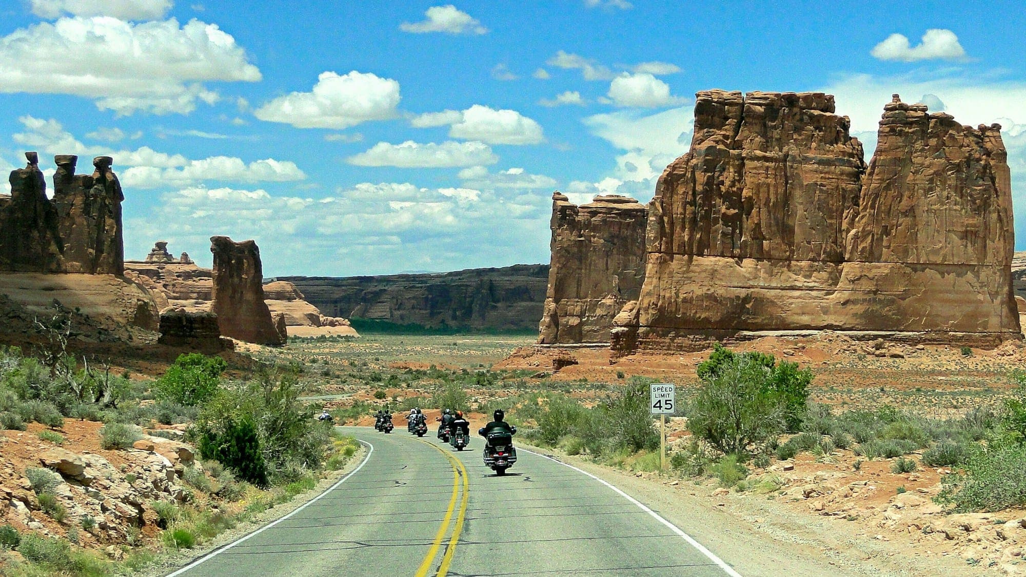 A group of riders on a two-lane road between red sandstone towers in Canyonlands National Park, Utah